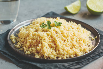 Couscous on a black ceramic plate on a table. The concept of vegetarian and healthy food.