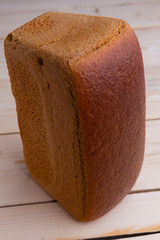 Brown brewed bread from rye flour in the form of brick, on wooden desk background, closeup, traditional russian