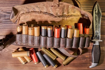 Muurstickers Old hunting cartridges and bandoleer on a wooden table © Vitalii Makarov