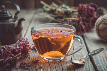 Cup of healthy echinacea tea, dry coneflower herbs and vintage teapot on wooden table.