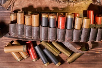 Tuinposter Old hunting cartridges and bandoleer on a wooden table © Vitalii Makarov