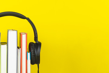 concept of audio book. headphone and books on yellow background