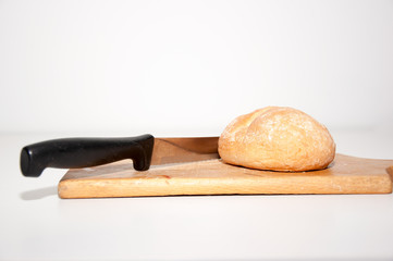 Hand cutting with a bun with a knife on a wooden chopping board