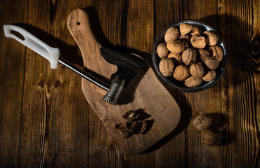 Walnuts in an old bowl with a kitchen ax on a wooden surface in rustic style