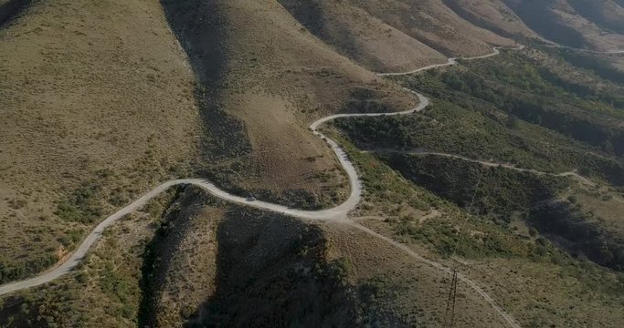 windy road on the base of the mountain and electric towers side to it. delvine albania -4k