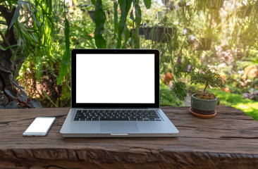 Outdoor office desk with laptop in the garden.Computer Laptop and tablet computer on the table blur background with bokeh, business technology concept ,Outdoor office desk with laptop in the garden.