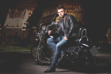 Cute biker in leather jacket is sitting on a motorcycle