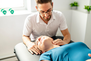 A Modern rehabilitation physiotherapy man at work with woman client woking on neck