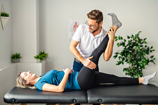 A Modern rehabilitation physiotherapy man at work with woman client working on leg