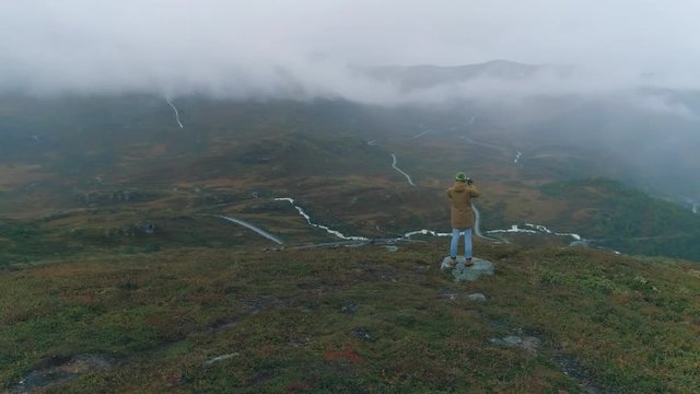 Woman using smartphone to share mountain epic view in Norway
