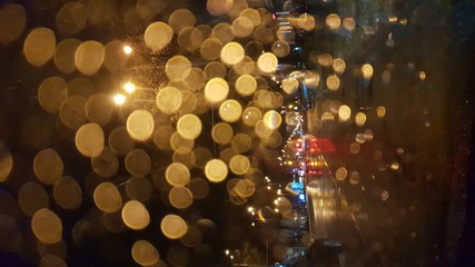 Rain drops on window with road light bokeh, City life in night in rainy season abstract...