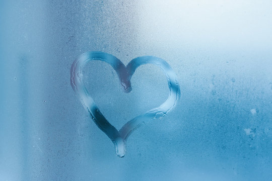 Heart on the glass and drops of water. Condensation on the window