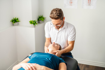 A Modern rehabilitation physiotherapy man at work with woman client working on neck