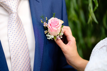 Bride putting on flowers boutonniere on groom