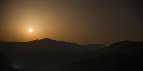 Panorama of mountains with full moon on night sky and stars