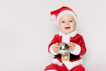 Beautiful little baby celebrates Christmas. New Year's holidays. Baby in a Christmas costume holding in her hands Christmas ball