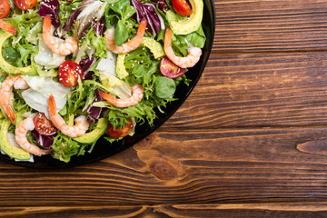 Mix of salad with shrimps , avocado and cherry tomatoes . Healthy food background