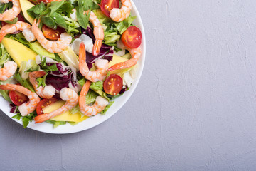 Mix of salad with shrimps , avocado and cherry tomatoes . Healthy food background