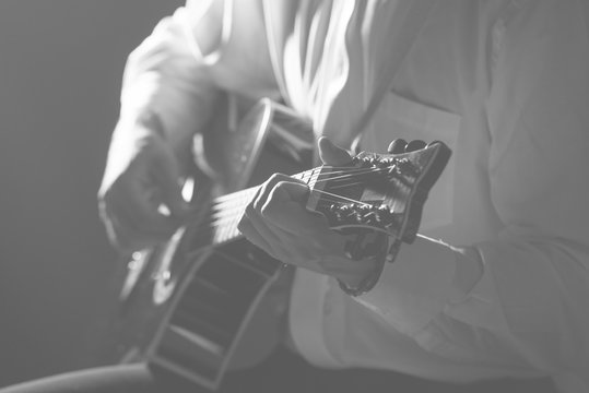 Musician plays guitar hands on strings close up. Theme music.    