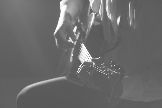 Musician plays guitar hands on strings close up. Theme music.     