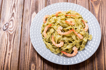 Pasta tagliatelle with sauce pesto and shrimps . Italian food background