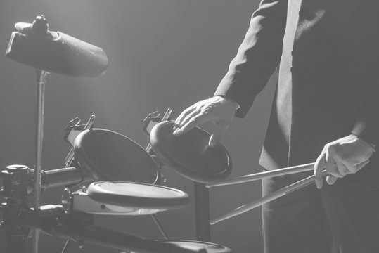 Drummer. The guy holds drum sticks in his hand against the background electronic drum. Young man with drum sticks.