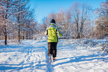 Running athlete woman sprinting in winter forest. Training outside in cold snowy weather.