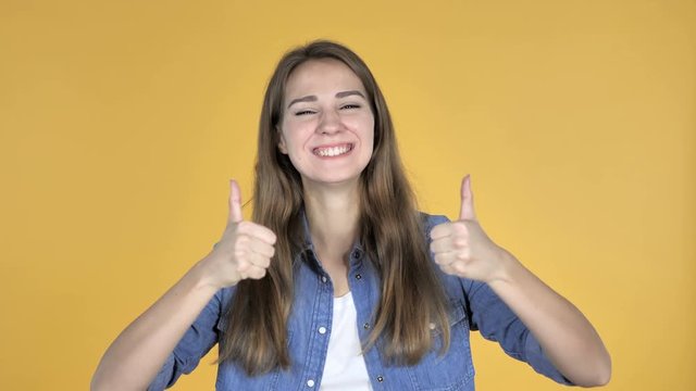 Pretty Woman Gesturing Thumbs Up Isolated on Yellow Background