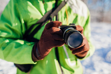 Fototapeta premium Young photographer takes pictures of winter forest using camera. Young man shooting photos outdoors