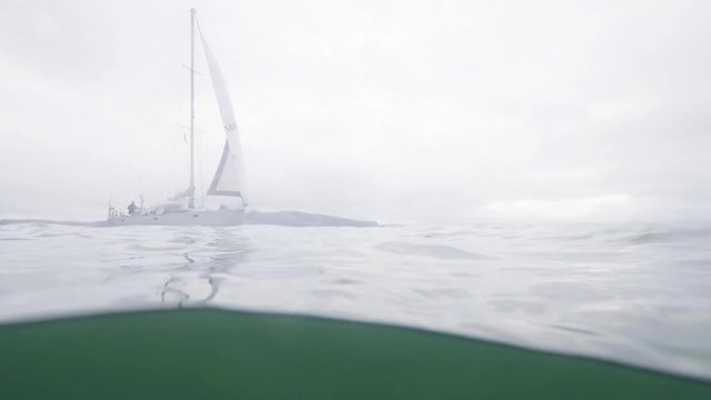 Waterline view sailing yacht in sea water on cloudy sky background