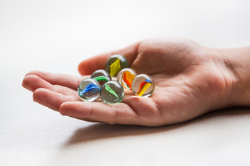 Colorful game marbles in the hand of a child on white background