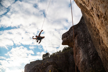 Man in hardhat hanging on rope while doing rappel and showing pirouettes flying in air © pablobenii
