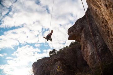 Man in hardhat hanging on rope while doing rappel and showing pirouettes flying in air © pablobenii