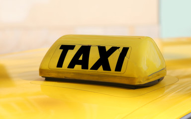 writting taxi in black on a yellow taxi