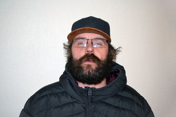 Portrait of a mustached and bearded man in glasses and a cap. Caucasian middle-aged.