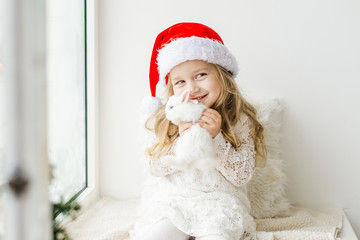 little girl in white dress with a little girl in red dress sitting by the window waiting for Christmas and Santa Claus