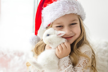 little girl in white dress with a little girl in red dress sitting by the window waiting for Christmas and Santa Claus