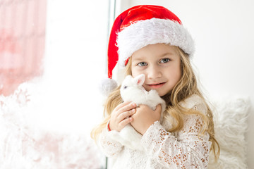 little girl in white dress with a little girl in red dress sitting by the window waiting for Christmas and Santa Claus