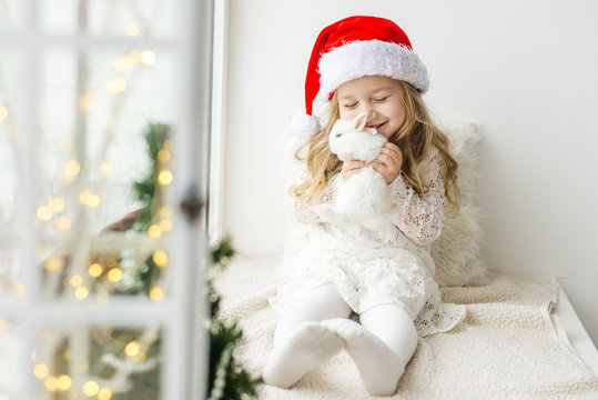 little girl in white dress with a little girl in red dress sitting by the window waiting for Christmas and Santa Claus