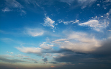 Naklejka na ściany i meble White curly clouds in a blue sky. Sky background sunset