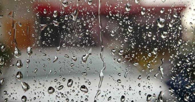 Raindrops water on window glass pane in rainy season. Selective focus. Water of Raindrops splashing on outer surface of window in pouring rain