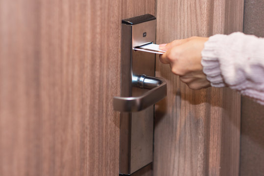 Woman hand inserting card to open electronic lock in hotel door