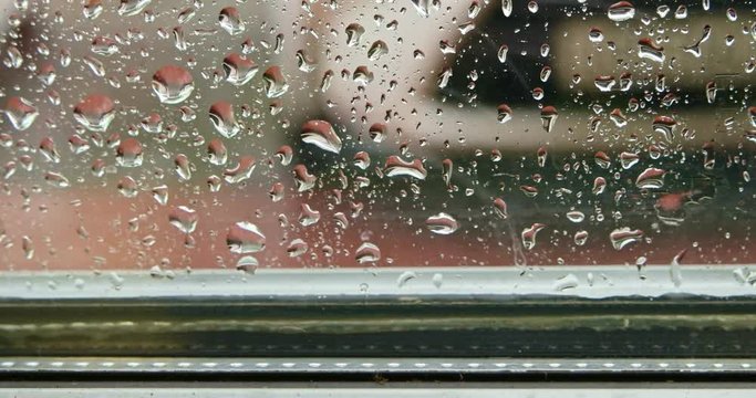Water on window glass pane in rainy season. Selective focus. Water of Raindrops splashing on outer surface of window in pouring rain, rainfall