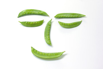 Pisum sativum on a white scene arranged as a face [concept Vegetables have health benefits]