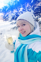 Beautiful attractive blonde with a glass of champagne in her hands celebrates the New Year and makes selfie on smartphone