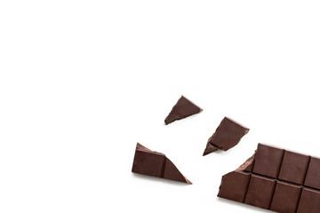 Broken dark chocolate bar isolated on white table. Horizontal composition. Top view