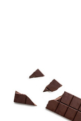 Broken dark chocolate bar isolated on white table. Vertical composition. Top view