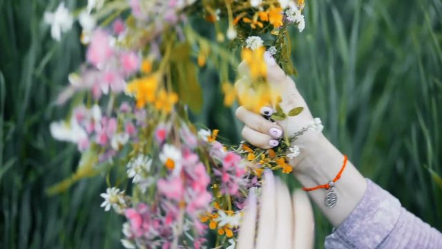 Flowers in the field. Girl in the field. Pagan Slavic rite. Pagan rite. Paganism. Girl making a wreath. Girl sorting the wildflowers. Girl binding the flowers.