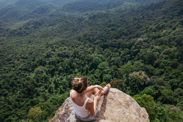 Young lady hiker sitting on top of a mountain