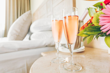 Two glasses of rose champagne in the upscale hotel room. Dating, romance, honeymoon, valentine, getaway concepts